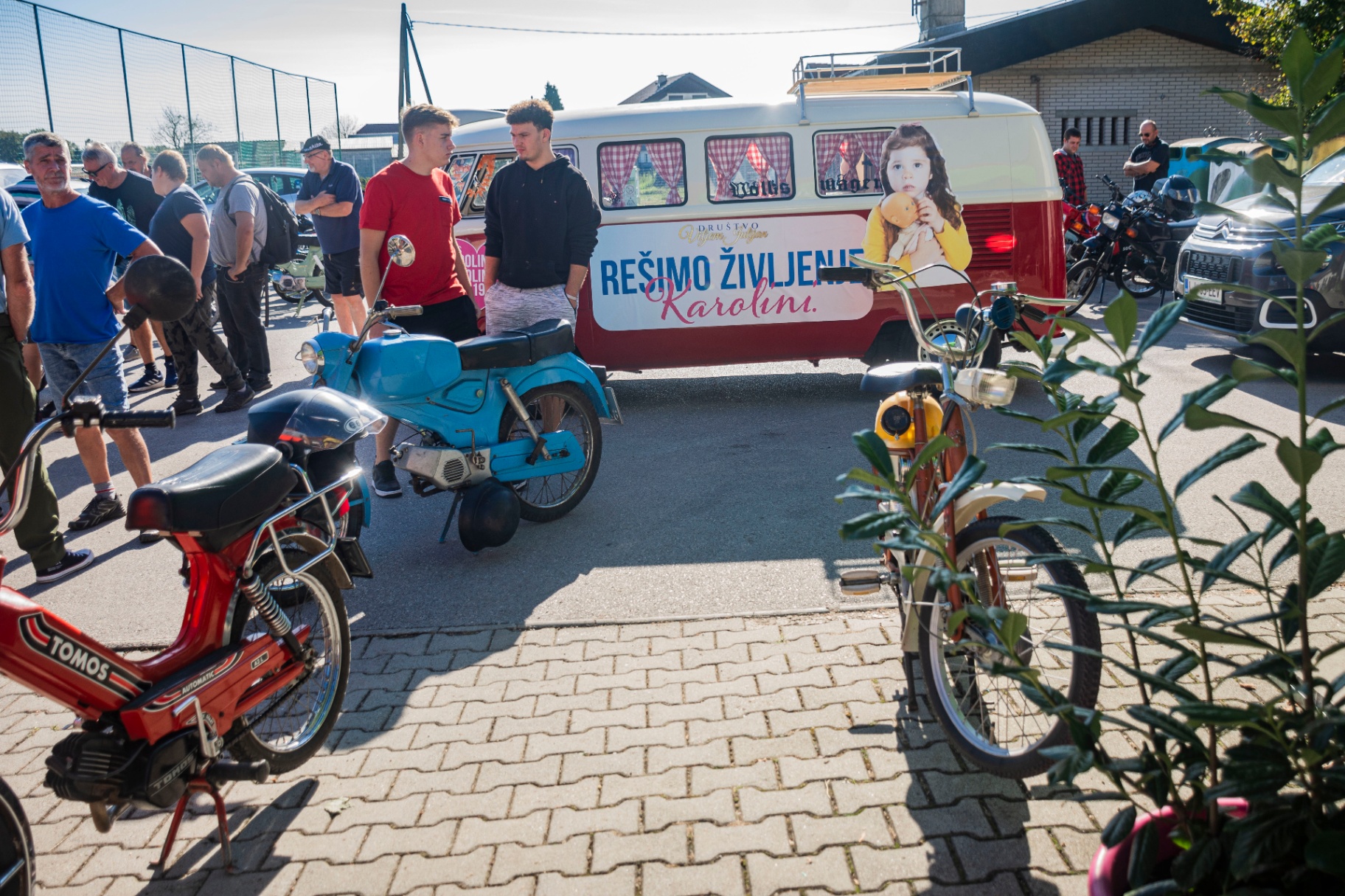 Moder starodobni moped pred humanitarnim kombijem
