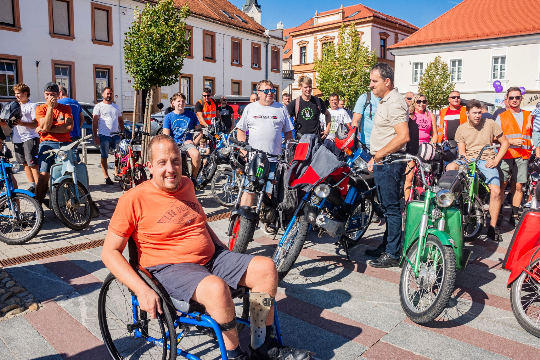 Udeleženec na invalidskem vozičku med prijatelji z mopedi