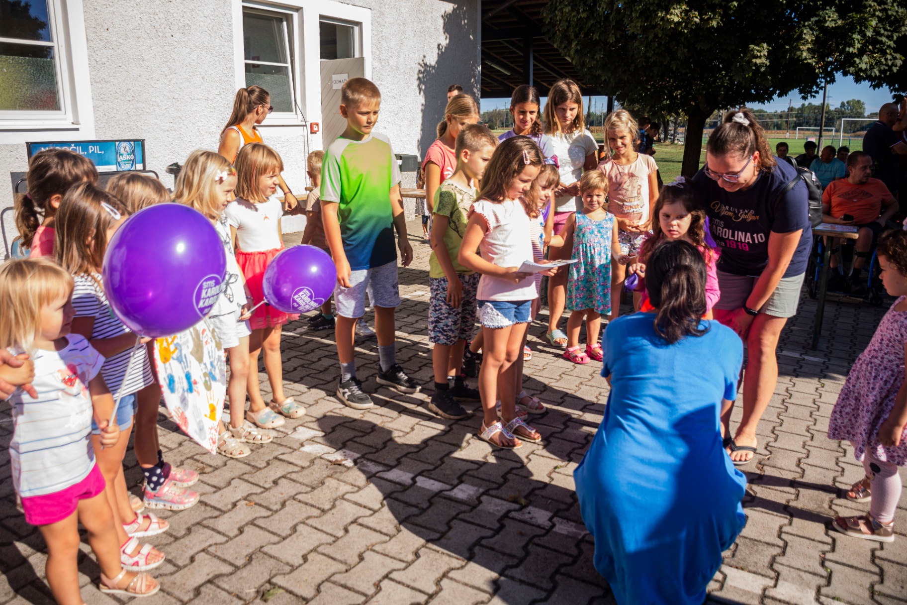 Otroci z vijoličnimi baloni v vrsti za darila