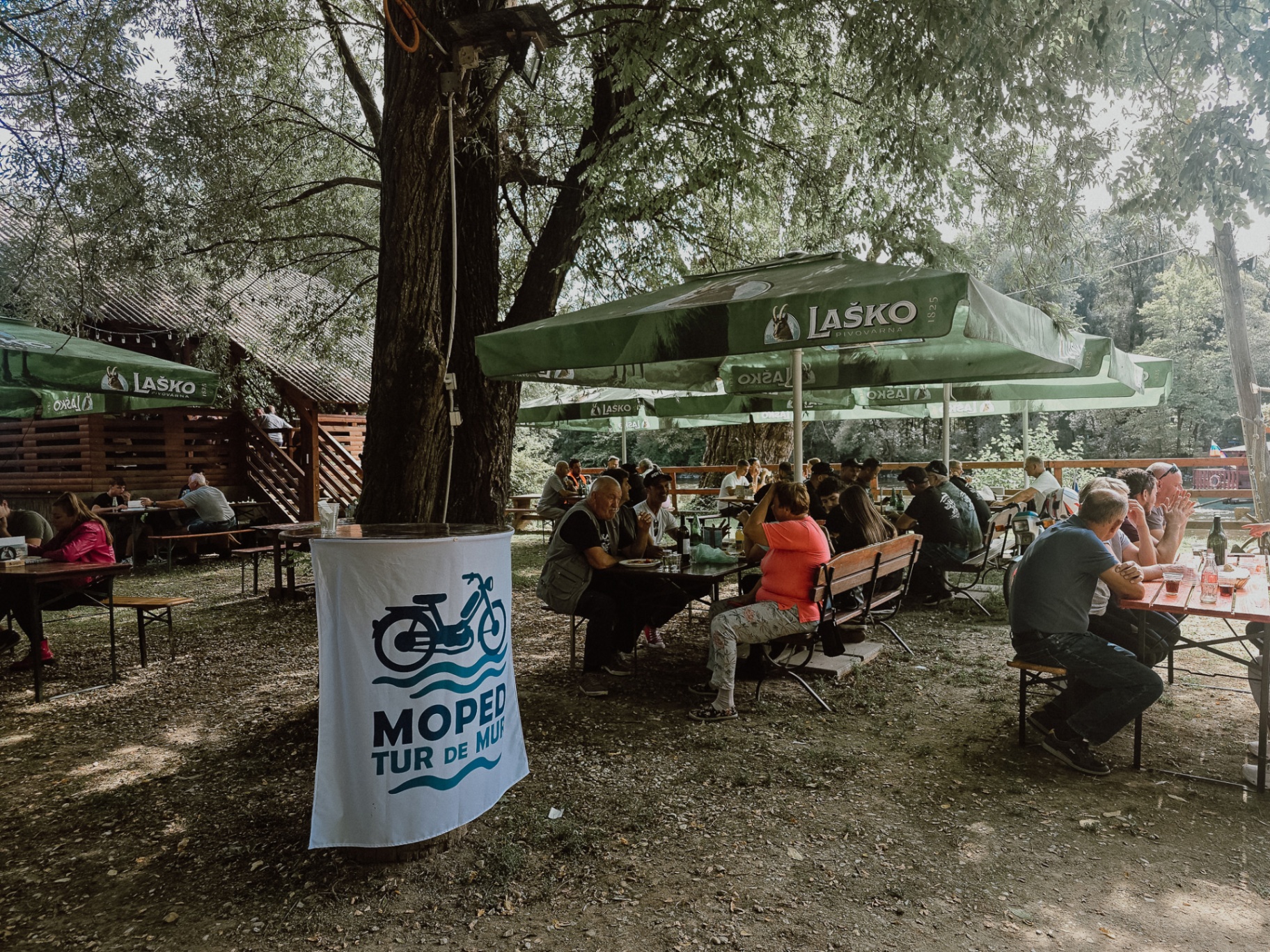 Zastava MOPED Mur pred gostinskim prostorom pod drevesi