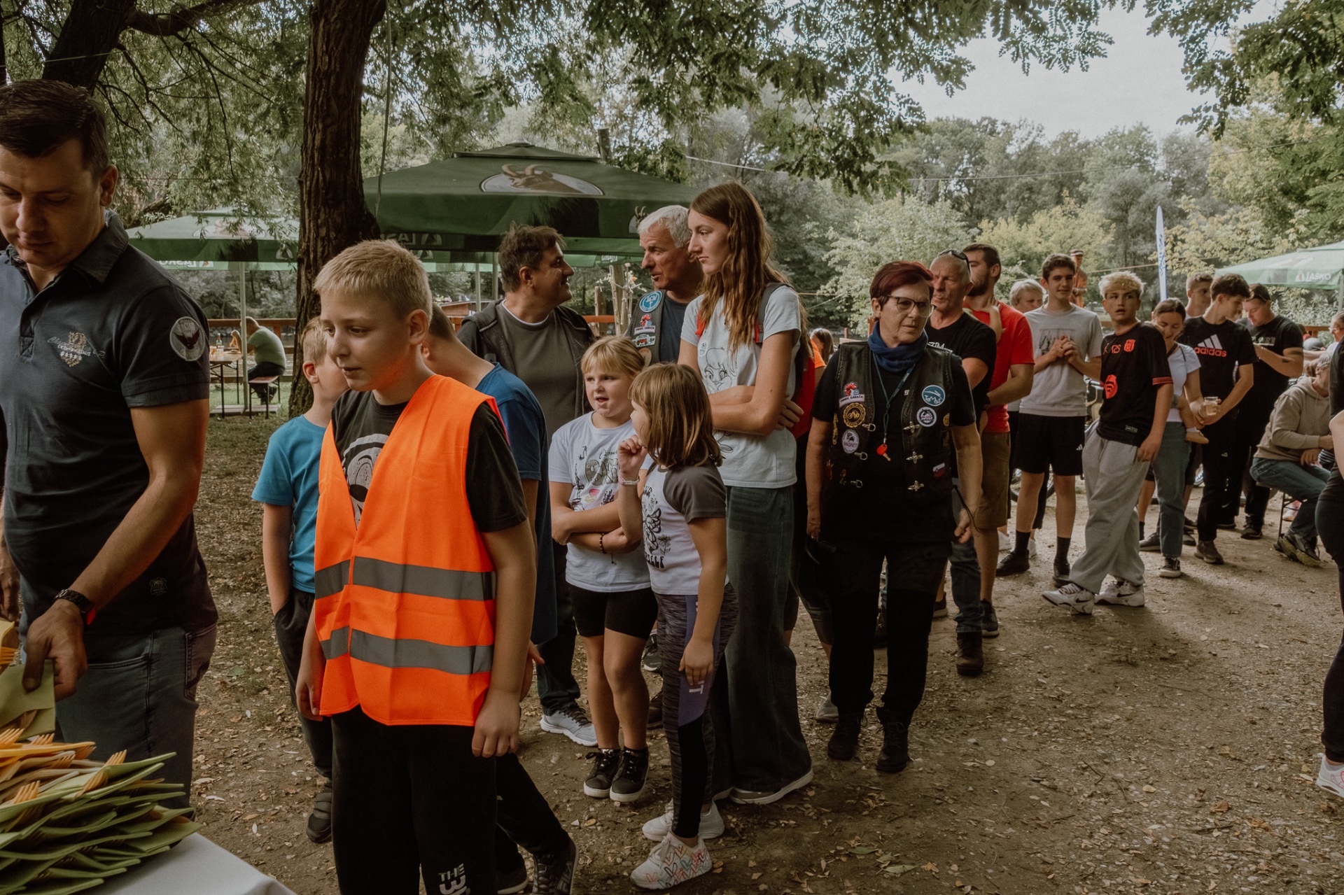 Otroci v oranžnih odsevnih jopičih med udeleženci na postanku